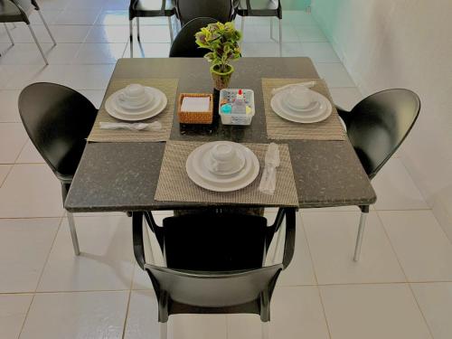 a table with black chairs and white plates on it at Pousada Marahub in Maragogi
