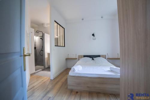 una camera da letto con un letto con lenzuola bianche e uno specchio di "Nid douillet" a Antibes