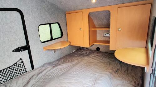 a small room with a bed and a mirror at Darwin Teardrop Caravan for Hire from ElectricExplorers in Hawkshead