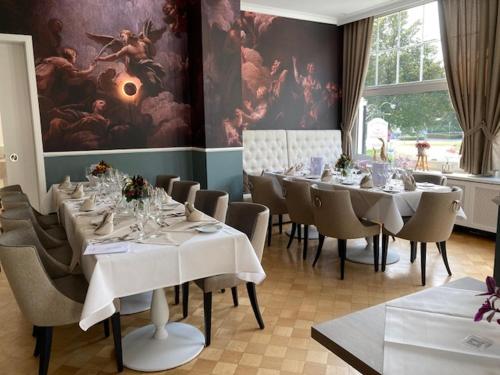 a dining room with white tables and chairs and a painting at Alte Villa Schlossblick in Bad Pyrmont