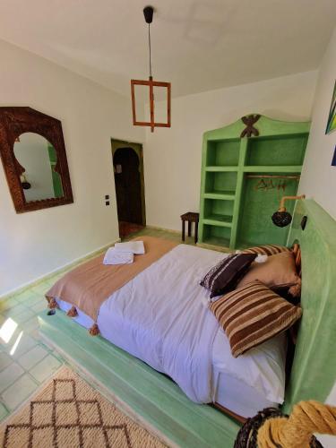 a bedroom with a large bed with a green headboard at Villa Nouran - Chambre Hôte in Ghazoua
