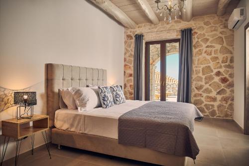 a bedroom with a bed and a stone wall at Ioanna Château - Luxury Stone Villa in Maryiés
