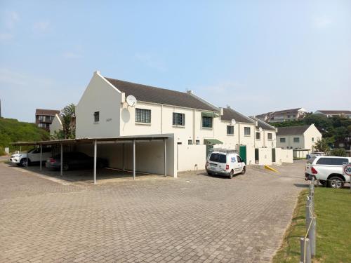 a large white building with cars parked in a parking lot at 61 Settler Sands - Beach apartment in Port Alfred
