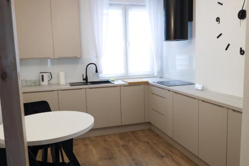a kitchen with white cabinets and a table and a window at Apartament Komfort in Słupsk