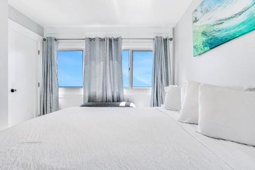 a white bedroom with a large bed with a window at Pinnacle Port Penthouse 10 in Panama City