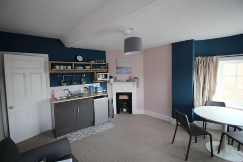 una cucina con pareti blu e tavolo con sedie di Pier View 2 Bedroom Apartment a Cowes