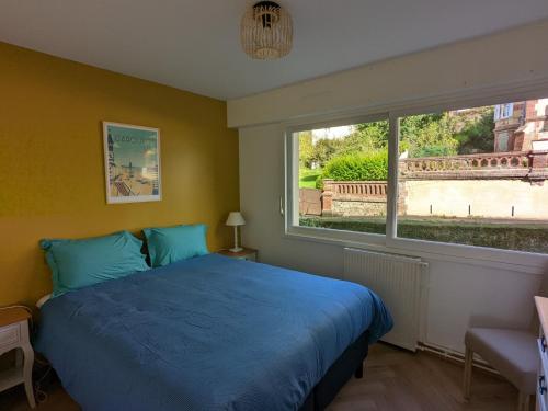 a bedroom with a blue bed and a window at Les Tennis - Superbe appartement avec parking in Houlgate