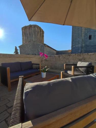 une terrasse avec des canapés, des tables et un parasol dans l'établissement Uzès Centre Historique, Terrasse Privative Panoramique, à Uzès