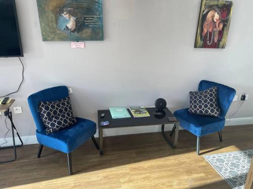 two blue chairs and a table in a room at Immaculate 1-Bed Studio with outside patio in Brighouse