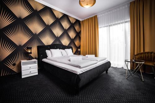sypialnia z dużym łóżkiem z czarno-złotą ścianą w obiekcie Południk Park Boutique Hotel Conference&SPA w mieście Stargard
