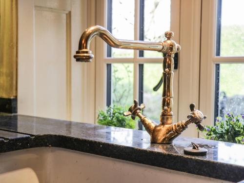 a kitchen sink with a gold faucet at Bute Cottage in Pickering