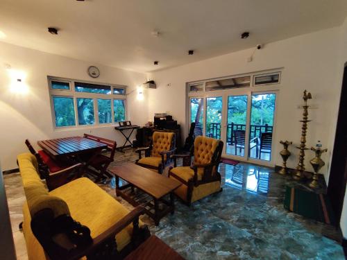a living room with chairs and a table and windows at Y&Y Residence in Kandy