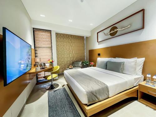 a bedroom with a bed and a flat screen tv at Morvee Hotels Alipore Kolkata in Kolkata