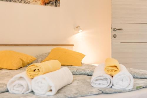 1 cama con toallas blancas y almohadas amarillas en Villa Sunny Home, en Galižana