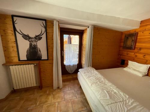 a bedroom with a bed and a picture of a deer on the wall at LE BLIZZARD Bel appartement avec grande terrasse dans vieille ferme de montagne rénovée in Les Orres
