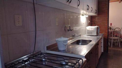 uma pequena cozinha com um lavatório e um fogão em Apartamento próximo aos principais pontos turísticos em Águas de Lindoia