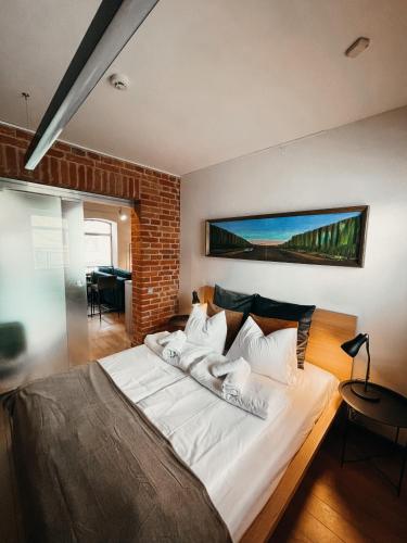 a bedroom with a large white bed with a brick wall at 1880 Apartment with Private Parking in Marijampolė