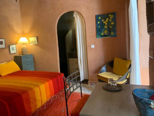 a bedroom with a bed and a table and a chair at RIAD CHANT D'ETOILES tadighoust in El Hara