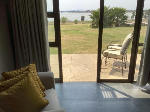 a living room with a couch and a chair outside a window at The Vaal Guesthouse in Oranjeville