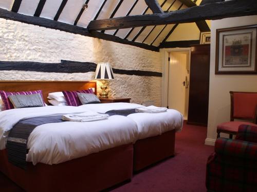 a bedroom with two beds and a table with a lamp at THE SARACENS HEAD INN in Amersham