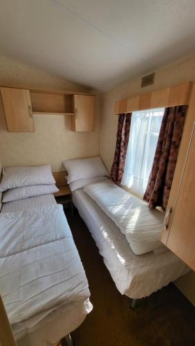 2 camas en una habitación pequeña con ventana en 19 Barnacre Scorton Six Arches caravan park, en Scorton