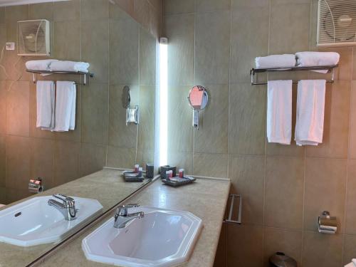 a bathroom with a sink and a mirror and towels at La Siesta Hotel Al Sokhna in Ain Sokhna