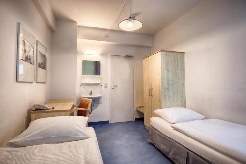 a bedroom with two beds and a desk and a sink at enjoy hostel Berlin City West in Berlin