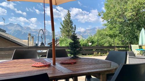 a wooden table with an umbrella on a patio at Chalet Martine in LʼHuez