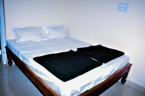 a bed with white sheets and a black blanket at Immanamane Homestay in Chikmagalūr