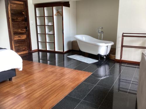 a bathroom with a tub and a wooden floor at The Vaal Guesthouse in Oranjeville