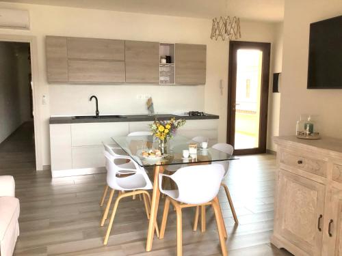 a kitchen with a table and white chairs in a room at Oasi delle Onde in Villasimius