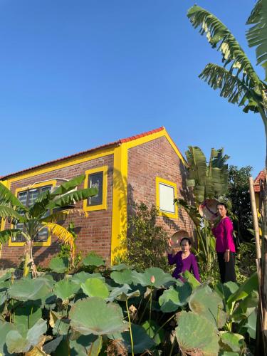 two people standing in front of a house with plants at Ninh Binh Royal Homestay in Ninh Binh