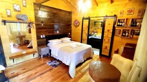 a bedroom with a white bed and wooden walls at Pousada Caminhos da Natureza in Urubici