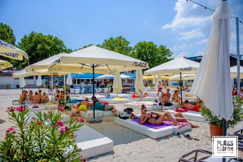 grupa ludzi siedzących na plaży z parasolami w obiekcie Holiday home in Siofok - Balaton 43127 w Siófoku