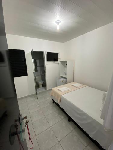 a bedroom with a bed and a bathroom with a tv at Pousada Vela Mar in Maragogi
