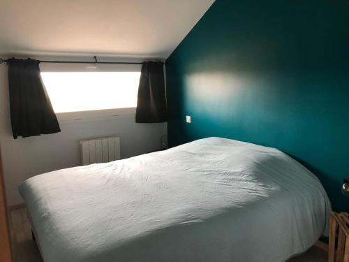 a bedroom with a white bed and a blue wall at Le logis du Chesnot in Saint-Quentin-sur-le-Homme