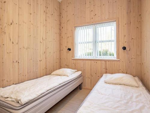 2 camas en una habitación con paredes de madera y ventana en Holiday home Sæby CXXV, en Saeby