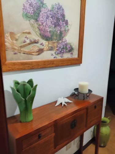 a wooden table with a vase of purple flowers on it at Quina'sHouse in Rossio ao Sul do Tejo