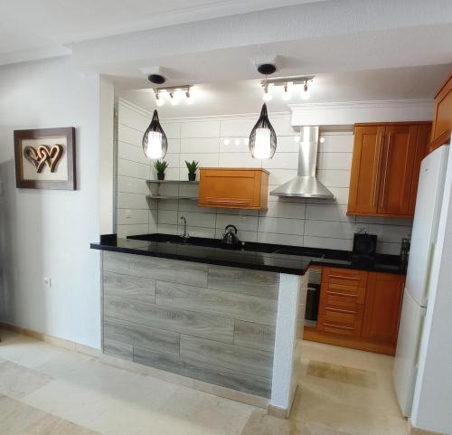 una cocina con encimera negra y armarios de madera en Villamartin Townhouse 1 minute walk to villamartin plaza en Villamartin