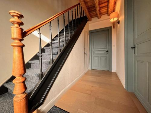 a hallway with a staircase with a wooden stair case at Gezellige Typisch Ardense woning met jacuzzi en grote afgesloten tuin in prachtige omgeving in Houffalize