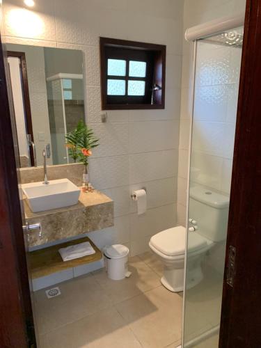 a bathroom with a toilet and a sink and a mirror at Pousada Chale Cana Brava in Guaramiranga