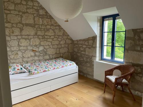 sypialnia z łóżkiem, krzesłem i oknem w obiekcie La Rigottiere w mieście Huismes