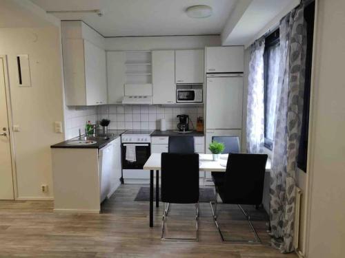 a kitchen with white cabinets and a table and chairs at Style 2BR appartment in Tornio city in Tornio