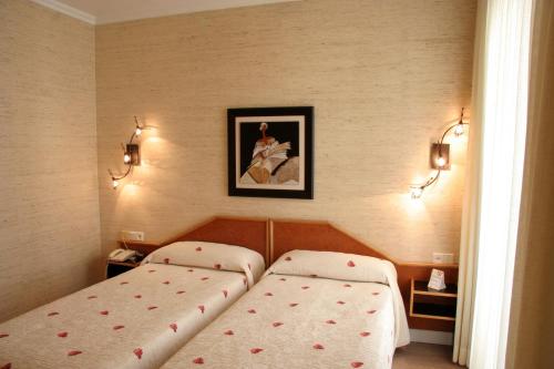 a bedroom with two beds and a picture on the wall at Hostal Paris in Valladolid