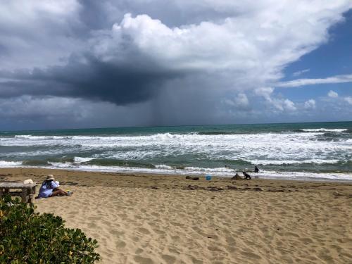 a group of people sitting on a beach near the ocean at Residencial Mañanero in Cabarete