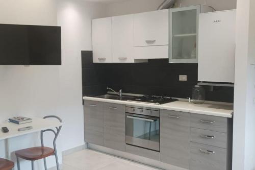 cocina con armarios blancos, fregadero y mesa en Faber B&B - Riserva Naturale Zompo lo Schioppo en Morino