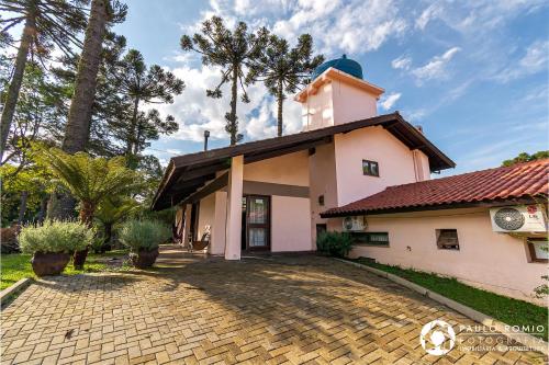 ein Gebäude mit einem Turm und einer steinernen Einfahrt in der Unterkunft Jardins de Canela - Aptos e Casas Bairro Nobre em Canela in Canela