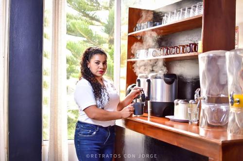 una mujer parada en una cocina con cafetera en Diesbu Hotel, en Marcala