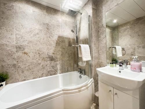 y baño con bañera blanca y lavamanos. en Spacious Flat Sleeps 8 near Princes Street en Edimburgo