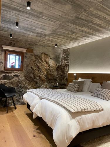 1 dormitorio con 1 cama grande y pared de piedra en Era del Rafel, en Escaldes-Engordany
